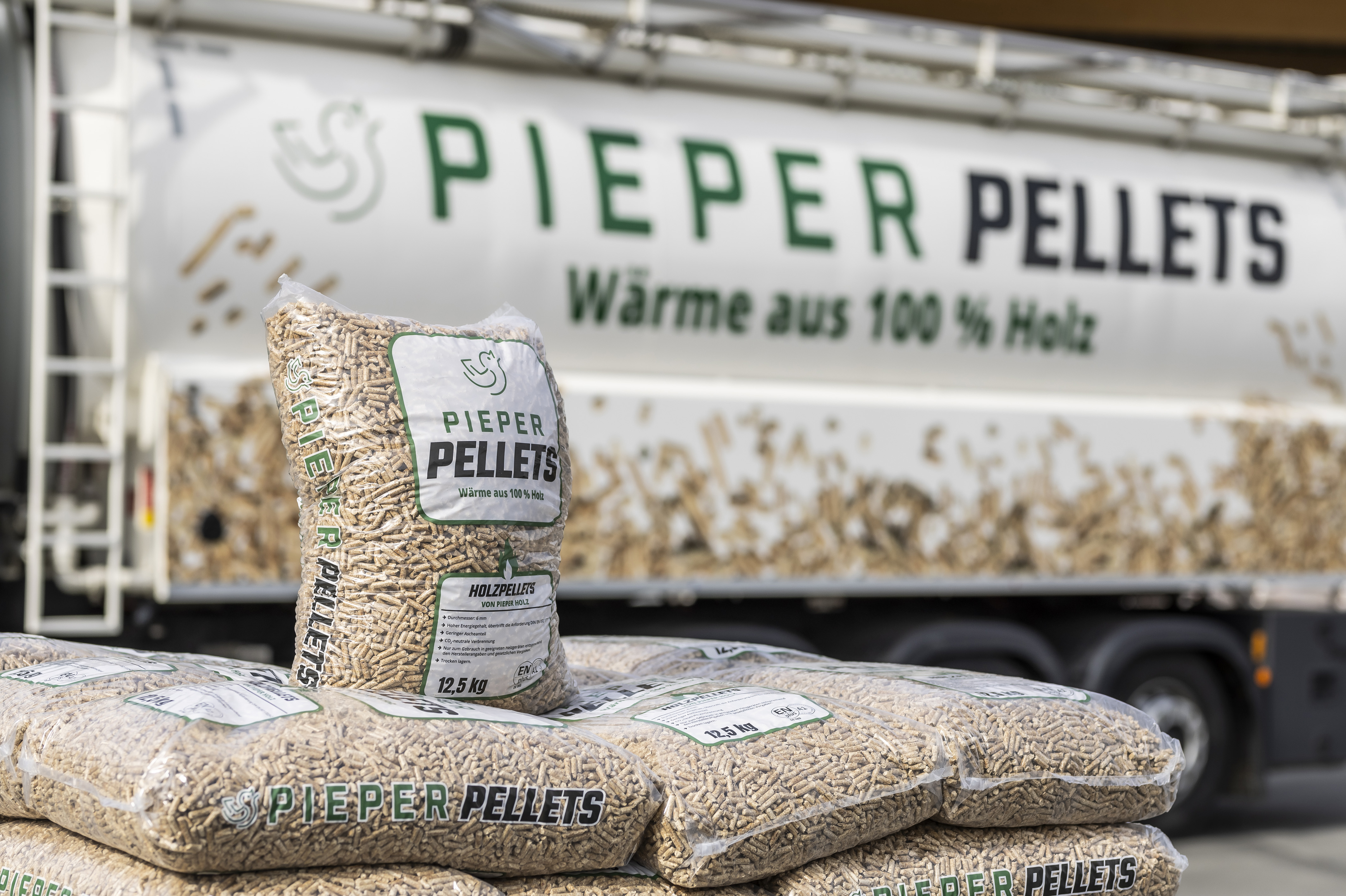 Kunststoffsäcke mit Pieper Holzpellets vor einem Pelletsilo-LKW mit Firmenaufschrift